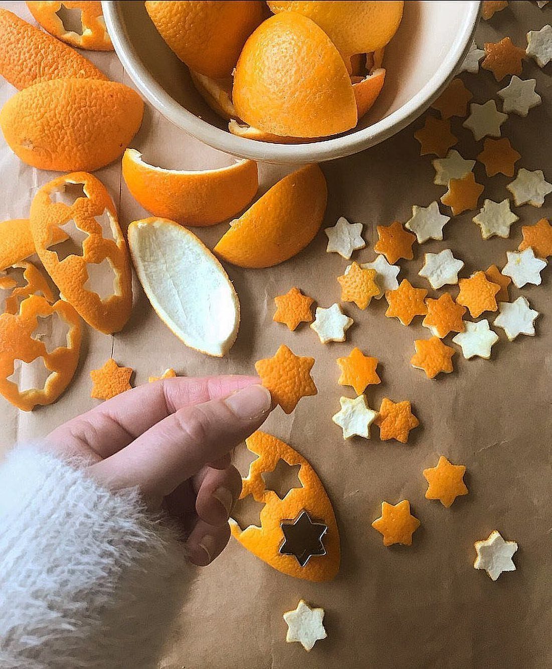 A hand picks up a star-shaped orange peel cutout among many other small star shapes.