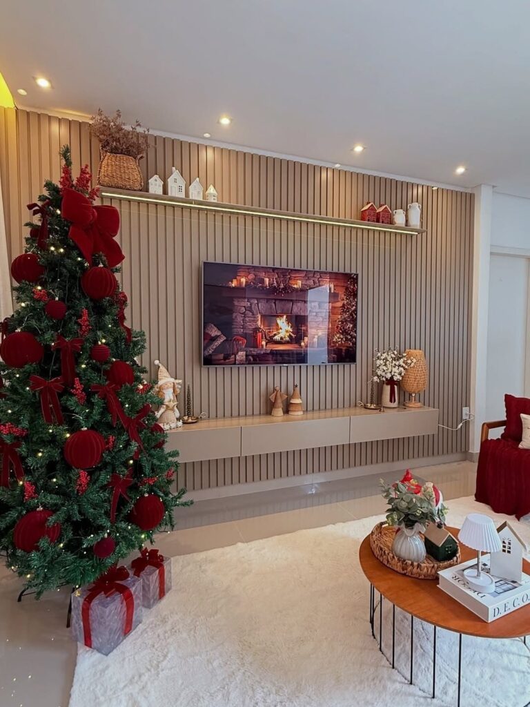 A decorated Christmas tree with red ornaments stands in a modern living room with a television.