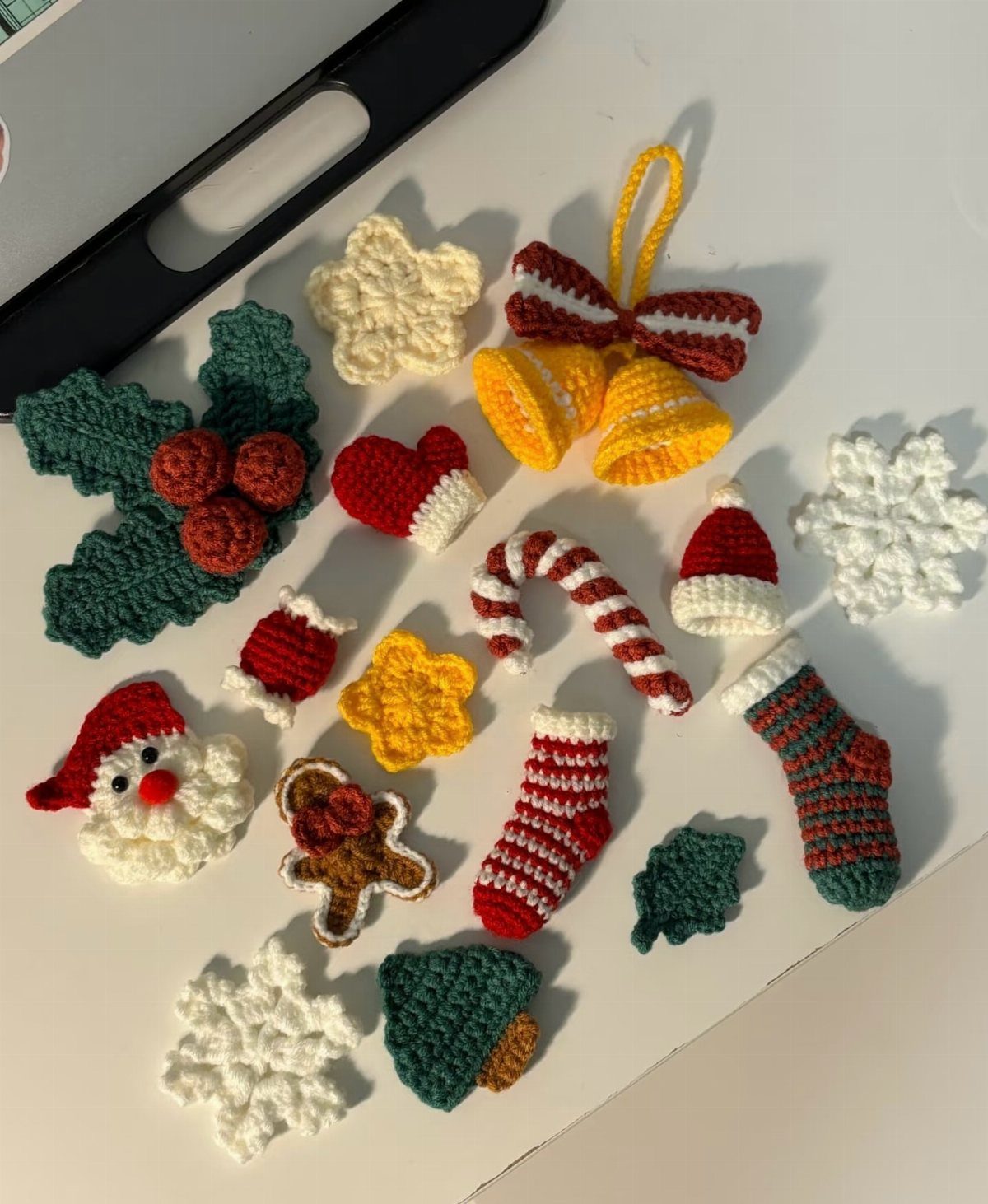Small handmade crochet Christmas ornaments like Santa, candy canes, and snowflakes scattered on a white background.