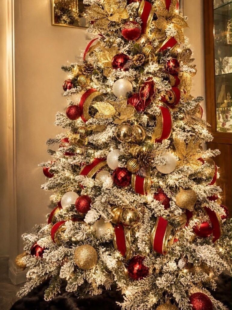 A frosted Christmas tree decorated with red, white, and gold ornaments and ribbons.