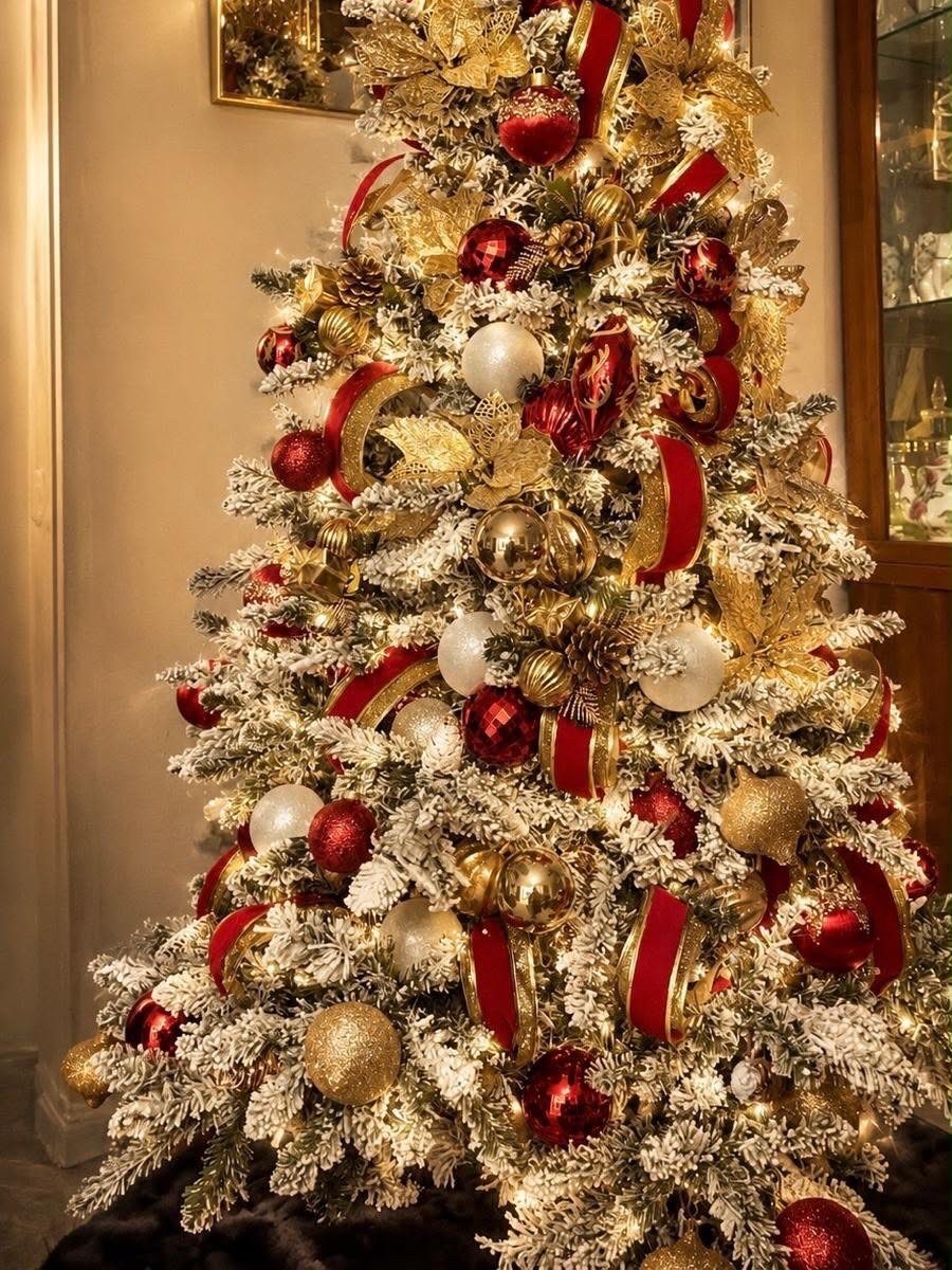 A frosted Christmas tree decorated with red, white, and gold ornaments and ribbons.